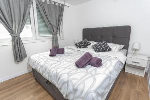 a bedroom with a large bed with purple pillows at Apartman Luka in Vinkovci