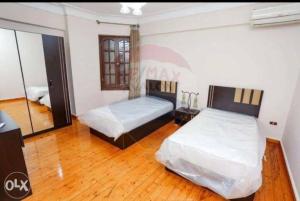 2 camas en una habitación con suelo de madera en Adorable Unique Furniture Flat, en Alejandría