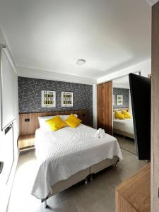 - une chambre avec un lit doté d'oreillers jaunes et d'un miroir dans l'établissement Moderno y delicado confort, à Santa Cruz de la Sierra