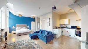 a living room with a blue couch and a kitchen at Glassford Residence in Glasgow