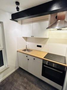 a kitchen with white cabinets and a sink and a stove at Bezauberndes Apartment im Herzen von Nieukerk. in Kerken