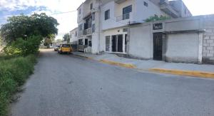 una calle vacía con una furgoneta amarilla estacionada al lado de un edificio en hospedaje Maluli suit 2, en Santa Elena