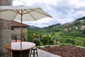 a table with an umbrella on a patio with a view at New Honey House, Serra do Marão Ansiães-Amarante in Amarante