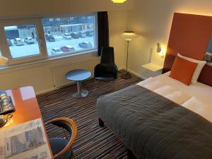 Pokój hotelowy z łóżkiem, biurkiem i oknem w obiekcie Hotel Hans Egede w mieście Nuuk