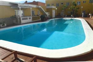 a large blue swimming pool in front of a house at Larimar Fuerteventura in Caleta De Fuste
