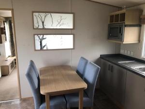 a small kitchen with a wooden table and blue chairs at The Sherbourne in Selsey