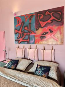 ein Schlafzimmer mit einem Gemälde über einem Bett mit Kissen in der Unterkunft Apartmány & Bistro 49 in Ostrava