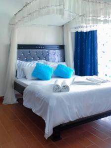 Sky Apartment kampala Feel At home في كامبالا: غرفة نوم بسرير ابيض مع مخدات زرقاء