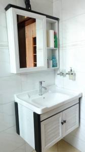 Sky Apartment kampala Feel At home في كامبالا: حمام مع حوض أبيض ومرآة