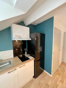 Il comprend une cuisine dotée d'un réfrigérateur noir et d'un mur bleu. dans l'établissement Appartement Cosy Hyper centre WIFI, à Rodez