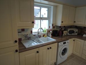 a kitchen with a sink and a washing machine at Sally's Garden in Warrenpoint