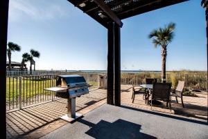 un patio con parrilla, mesa y palmeras en Ocean Villa 706 en Panama City Beach