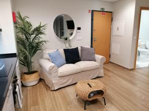een woonkamer met een witte bank en een spiegel bij Apartments Madeira Barreirinha in Funchal