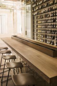 uma mesa longa com bancos e uma parede de garrafas de vinho em Hôtel de Tourrel, Saint Rémy de Provence, a Member of Design Hotels em Saint-Rémy-de-Provence