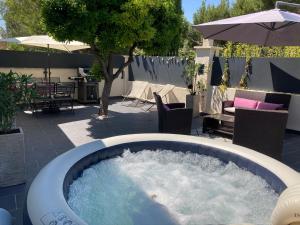 a hot tub in a patio with chairs and an umbrella at Key Largo villa 2p avec pkg clim grande terrasse avec jacuzzi proche port et plage in Bandol