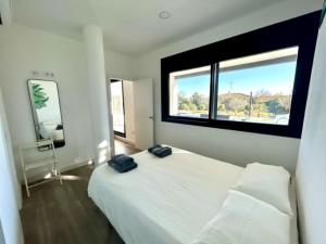 a bedroom with a white bed with two black towels on it at OLE TÚ ANDALUCIA in Sanlúcar la Mayor +54 photos
