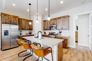 a kitchen with wooden cabinets and a white island with bar chairs at Luxurious Escape in Durango Mountain Resort
