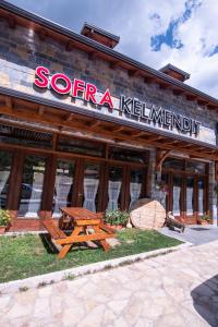 una mesa de picnic de madera frente a un restaurante en Sofra Kelmendit, en Tamarë