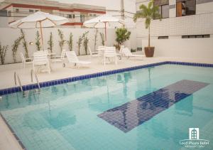 una piscina con sillas, mesas y sombrillas en Lord Plaza Hotel, en Teixeira de Freitas