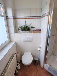 a bathroom with a toilet and a plant on the wall at Neu renoviert - Gemütliche Wohnung - 30 min bis Hamburg & Ostsee in Grönwohld