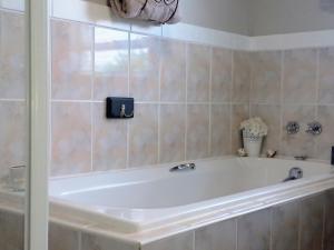 a white bath tub in a tiled bathroom at Silverdunes - GardenView in Bettyʼs Bay
