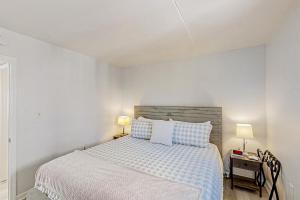 ein weißes Schlafzimmer mit einem Bett und zwei Lampen in der Unterkunft Gold Coast Cottage 407 in Myrtle Beach