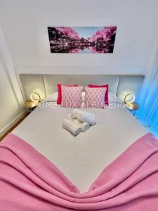 ein rosa und weißes Bett mit Handtüchern darauf in der Unterkunft Prime Lux Albufeira in Albufeira