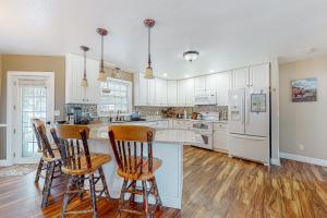 a kitchen with white cabinets and a kitchen island with chairs at Turkey Knoll House in Sturgis