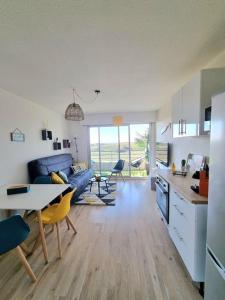 cocina y sala de estar con sofá azul y mesa en T2 face dunes et ocean - Proche Golf et Thalassothérapie, en Saint-Jean-de-Monts