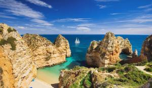 a sailboat in the ocean between some rocks at Holiday Albufeira in Albufeira