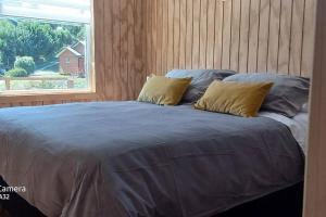 a large bed with two pillows and a window at Cabaña Los Maquis en Castro in Castro
