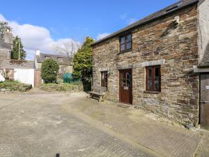 an old stone building with a bench in front of it at Keepers Cottage in Liskeard