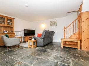 a living room with a couch and a television at Keepers Cottage in Liskeard