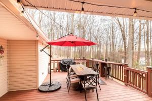 a patio with a table and an umbrella on a deck at Blue Mountain Lake Pocono House in East Stroudsburg