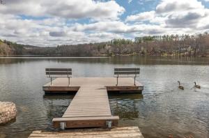 a dock with two benches and two ducks on a lake at Blue Mountain Lake Pocono House in East Stroudsburg