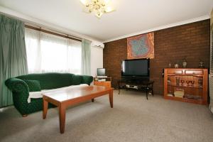 Una sala de estar con un sofá verde y un televisor. en Rent Melbourne, en Melbourne