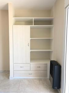 a closet with white shelves and a television in it at Duplex Boulevard in Viedma