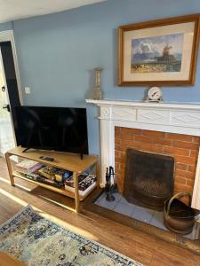 a living room with a fireplace and a television at 2 bedroomed fisherman’s cottage near quay in Blakeney
