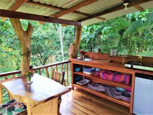eine Holzterrasse mit einem Tisch, einem Tisch und einem Baum in der Unterkunft Terra NaturaMa - off grid living in the jungle in Punta Uva