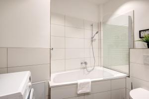 een witte badkamer met een bad en een douche bij Kaza Guesthouse, centrally located 2 & 3 bedroom Apartments in Augsburg in Augsburg