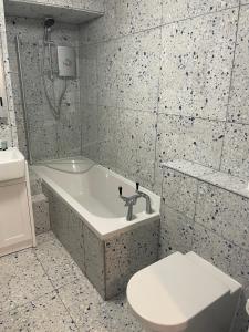 a bathroom with a tub and a toilet and a sink at 2 bedroomed fisherman’s cottage near quay in Blakeney