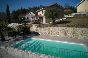 uma piscina em frente a uma casa em Quinta do Sol - Holiday Home in Gerês em Arcos de Valdevez