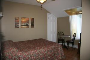 a bedroom with a bed and a table and chairs at Auberge Janine du Havre in Shippagan