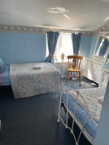 a blue bedroom with a bed and a chair at 2 bedroomed fisherman’s cottage near quay in Blakeney