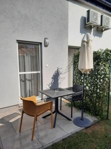 patio ze stołem, krzesłami i parasolem w obiekcie Silver Lelle Apartman Balatonlelle w mieście Balatonlelle