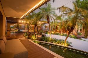 a house with a swimming pool and palm trees at Amazon Aeroporto Hotel in Cuiabá