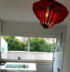 ein roter Kronleuchter hängt in einer Küche mit einem Fenster in der Unterkunft 140m2 Top FloorCentral Loft 24hr Self Check-in in Tirana