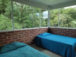 two beds in a room with a window at Finca La Primavera - Cabañas Campestres de Descanso in Sasaima