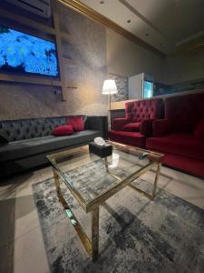 أجنحة ورد للشقق المخدومة في خميس مشيط: غرفة معيشة مع أريكة حمراء وطاولة زجاجية