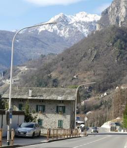 a street light with a building and a mountain at La pigna in Chiavenna